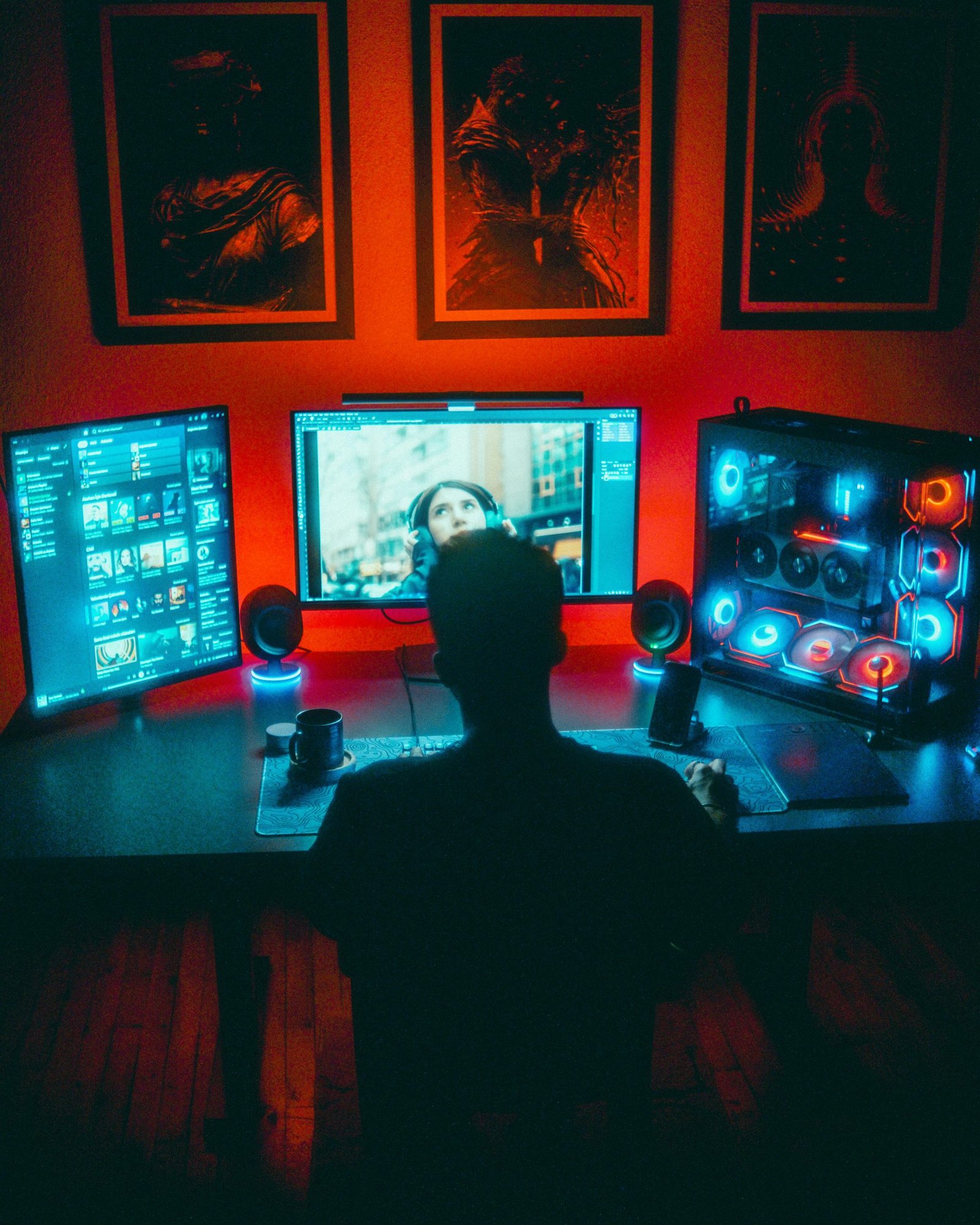 A gamer engrossed in a vibrant RGB computer setup with dual monitors at night.